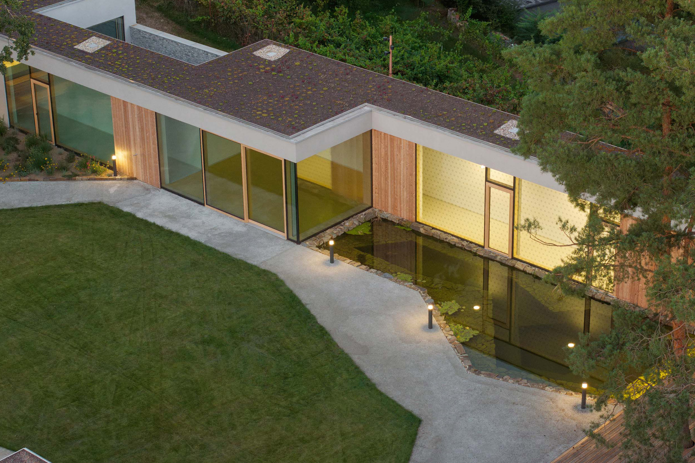 Betónovo šedé brúsené omietky StoSignature dopĺňajú drevené obklady smrekovcových biodosiek