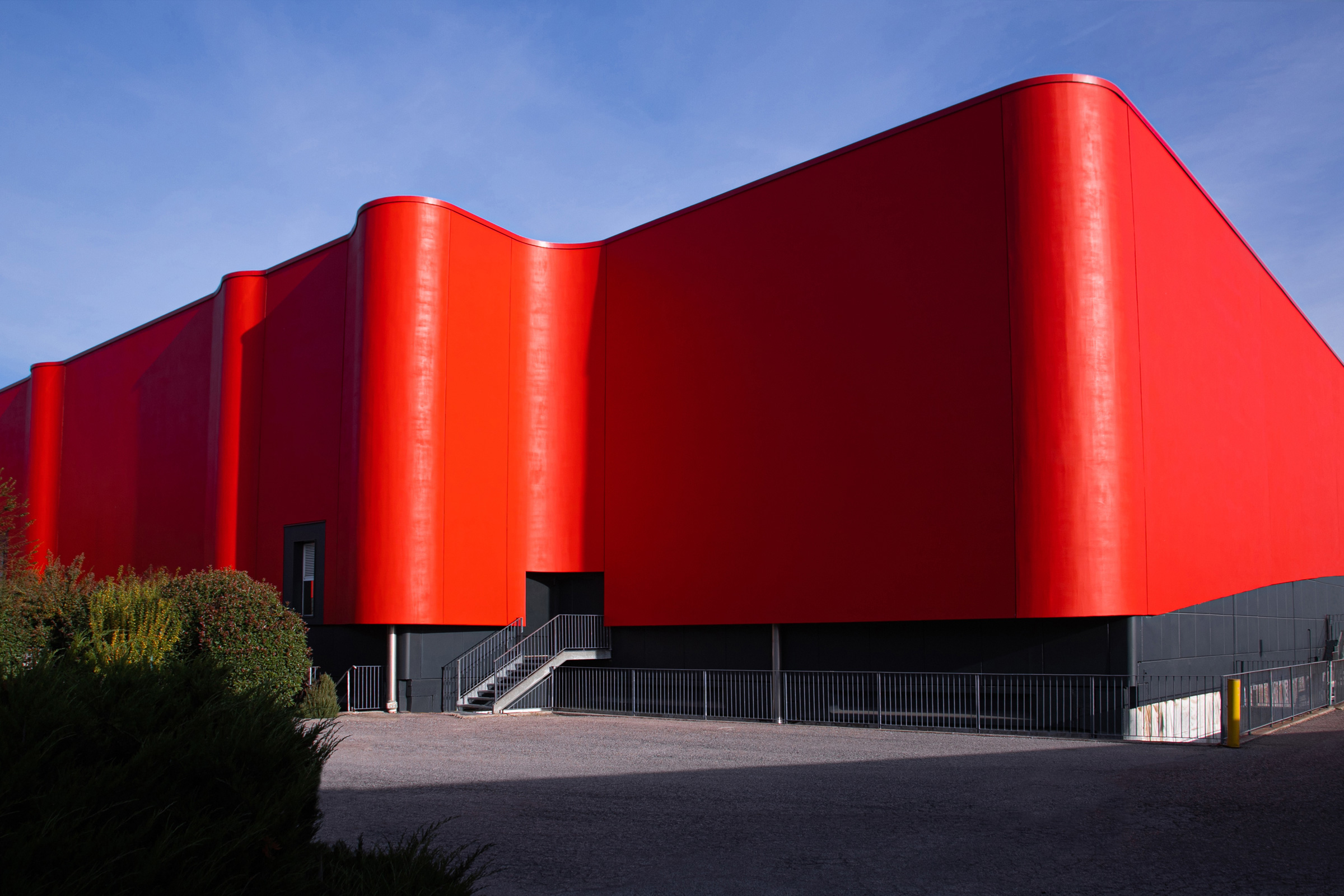 Budova s ikonickou červenou stuhou a odrazom na hladine jazierka.