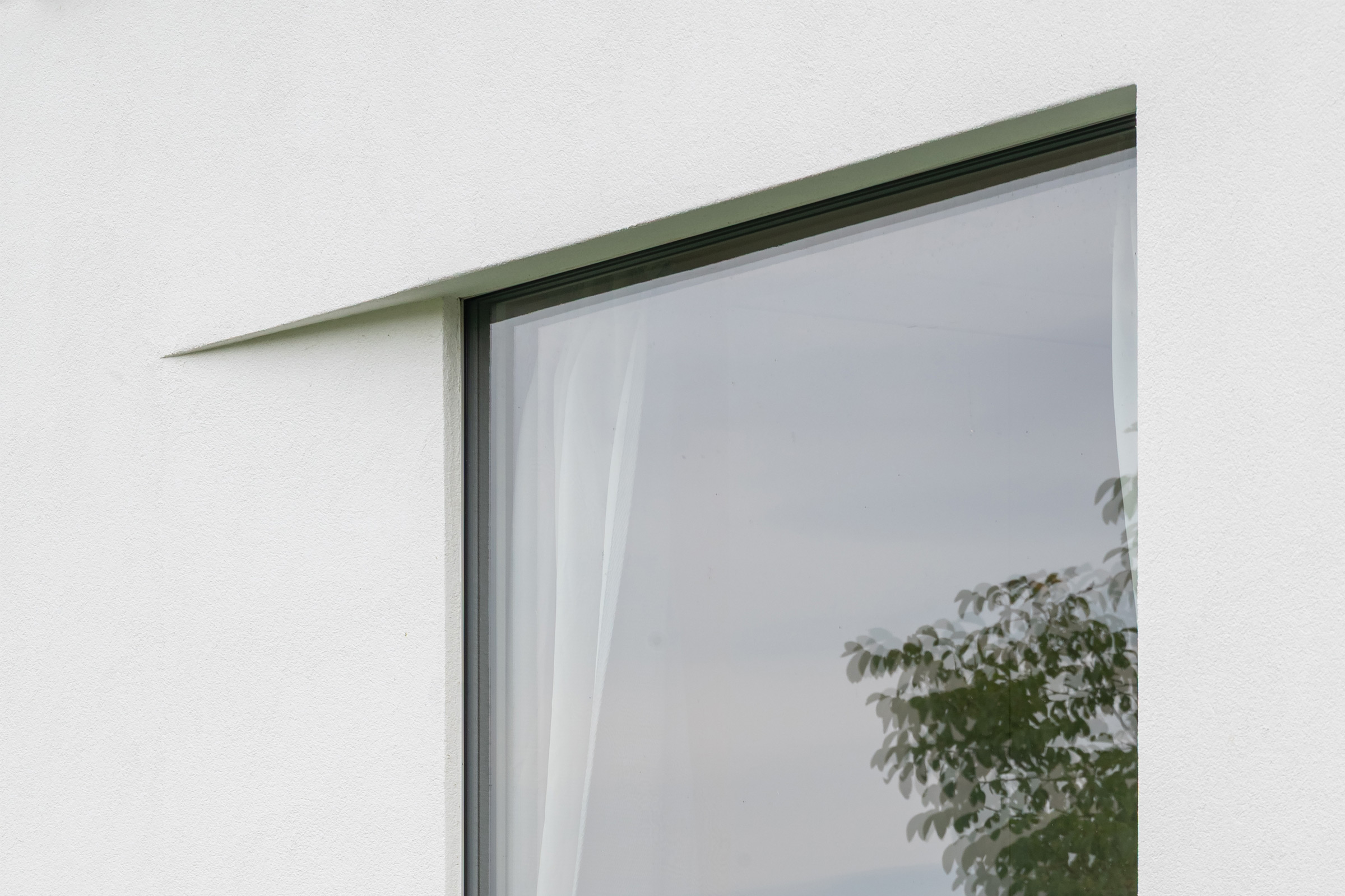 Detail bielej fasády s jemnými horizontálnymi profilmi StoDeco